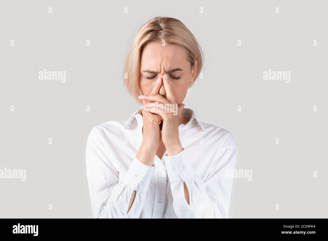 Donna d'affari matura che soffre di stress, stanchezza o mal di testa su sfondo chiaro Foto Stock