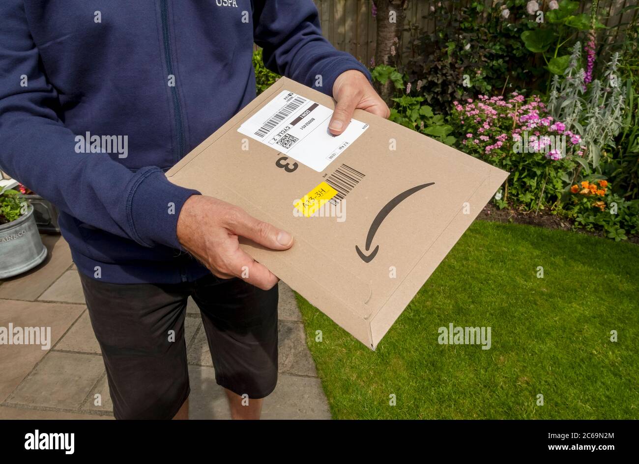 Primo piano di un uomo che tiene in mano il pacchetto di consegna Amazon Pacchetto home internet shopping Inghilterra Regno Unito GB Great La Gran Bretagna Foto Stock