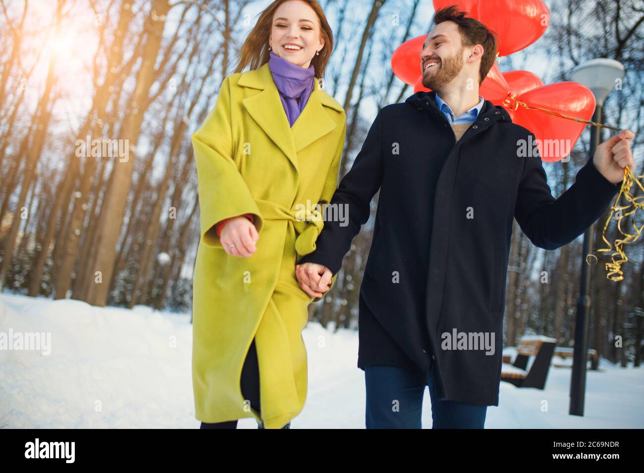 data romantica o anniversario di coppia a piedi, trascorrere il tempo insieme in strada invernale. uomo e donna felici insieme, tenere palloncini d'aria rossa in mani. Foto Stock