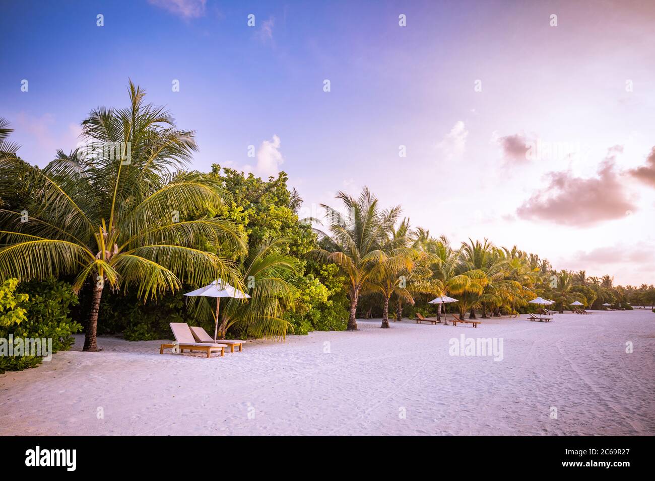 Splendido panorama tropicale del tramonto, due lettini sdraio ombrellone palma. Sabbia bianca, vista mare con orizzonte, cielo crepuscolo colorato, resort sulla spiaggia Foto Stock