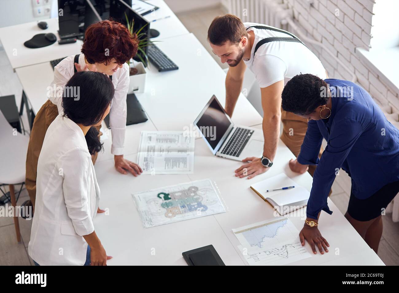 team internazionale creativo con computer, stand laptop e discutere questioni finanziarie di progetto aziendale Foto Stock