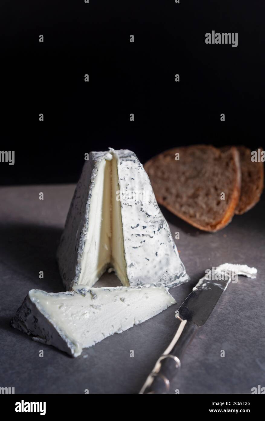 Una piramide di formaggio di capra ricoperta di cenere tagliata con toast di pasta acida Foto Stock