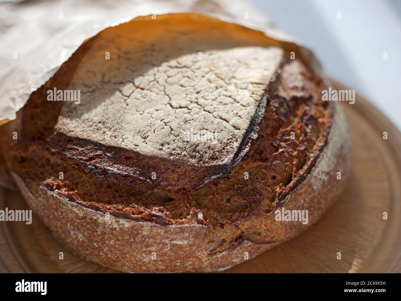 Una filone di pasta a base di segale in un sacchetto di carta su un pannello di pane Foto Stock