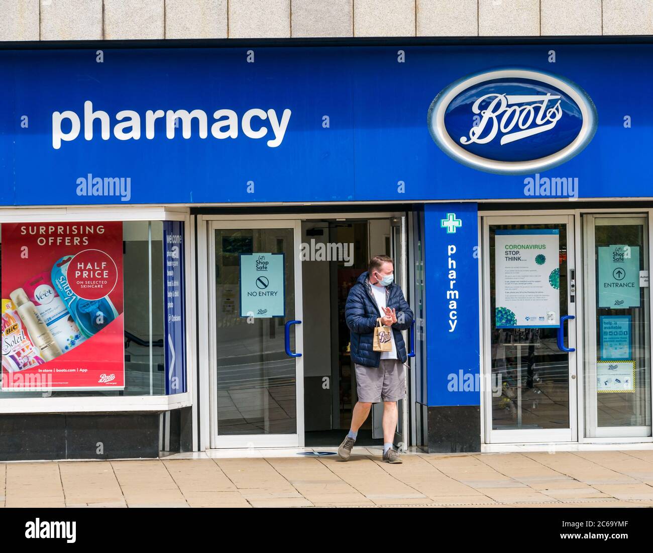 Edimburgo, Scozia, Regno Unito, 8 luglio 2020. Le maschere facciali sono la norma su Princes Street con sempre più persone che le indossano, soprattutto per andare nei negozi, anche se non diventano obbligatori nei negozi in Scozia fino a venerdì. Un uomo esce dagli stivali il negozio di farmacia indossando una maschera Foto Stock