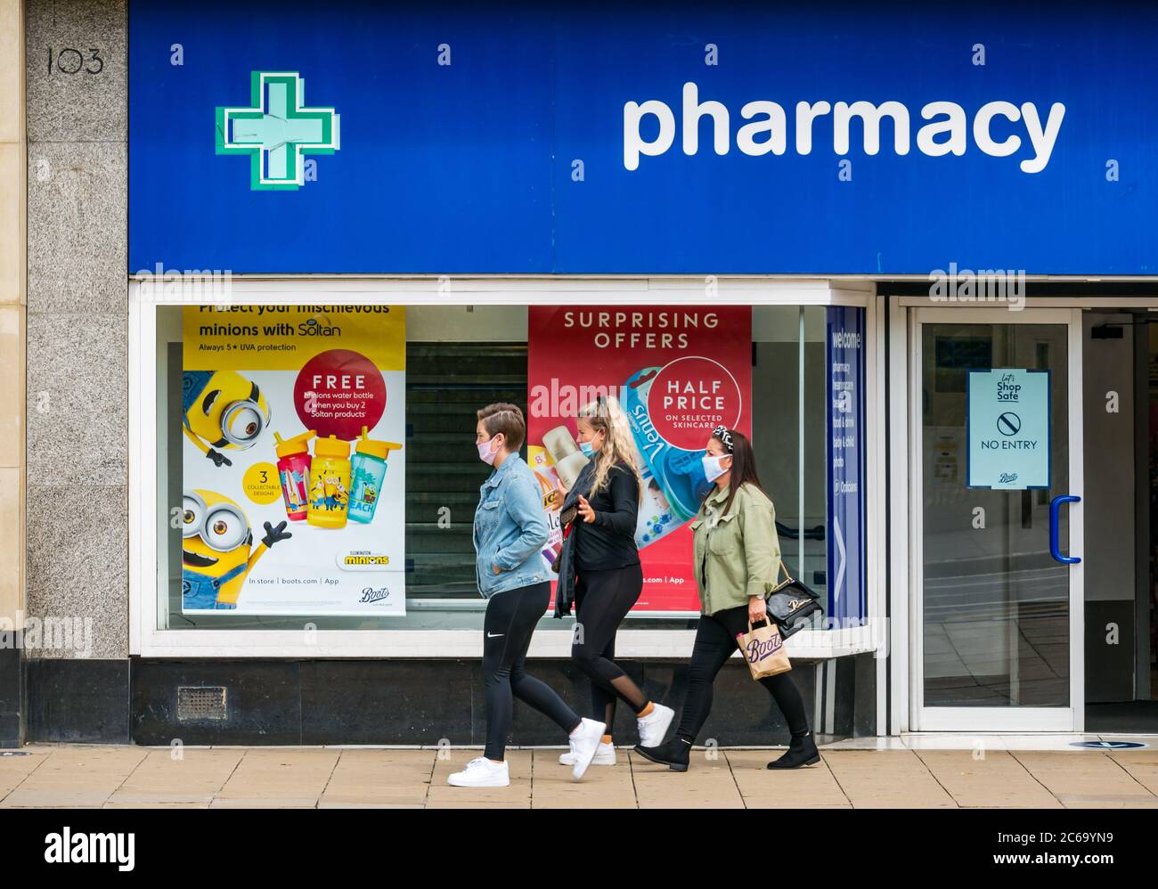 Edimburgo, Scozia, Regno Unito, 8 luglio 2020. Le maschere facciali sono la norma su Princes Street con sempre più persone che le indossano, soprattutto per andare nei negozi, anche se non diventano obbligatori nei negozi in Scozia fino a venerdì. Giovani donne che indossano maschere di fronte a piedi oltre Stivali il negozio chimico Foto Stock