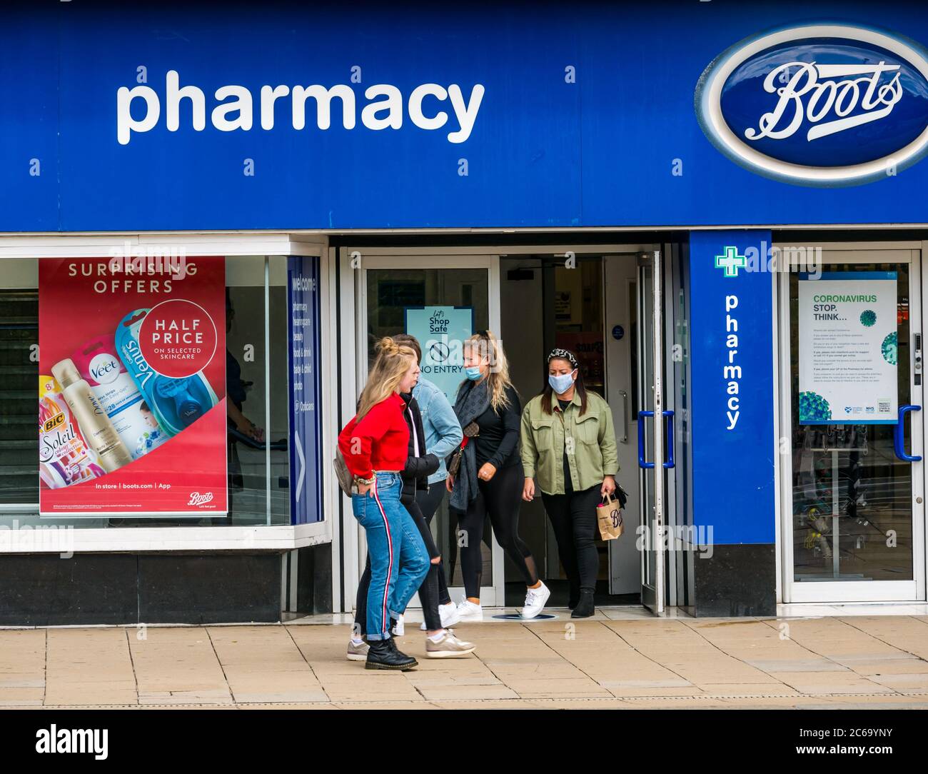 Edimburgo, Scozia, Regno Unito, 8 luglio 2020. Le maschere facciali sono la norma su Princes Street con sempre più persone che le indossano, soprattutto per andare nei negozi, anche se non diventano obbligatori nei negozi in Scozia fino a venerdì. Le giovani donne che indossano maschere facciali escono da Boots il negozio chimico Foto Stock
