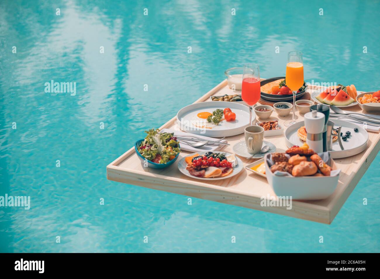 Colazione in piscina, colazione galleggiante in resort tropicale. Tavolo rilassante in acqua tranquilla piscina, sana colazione e frutta piatto presso la piscina del resort Foto Stock