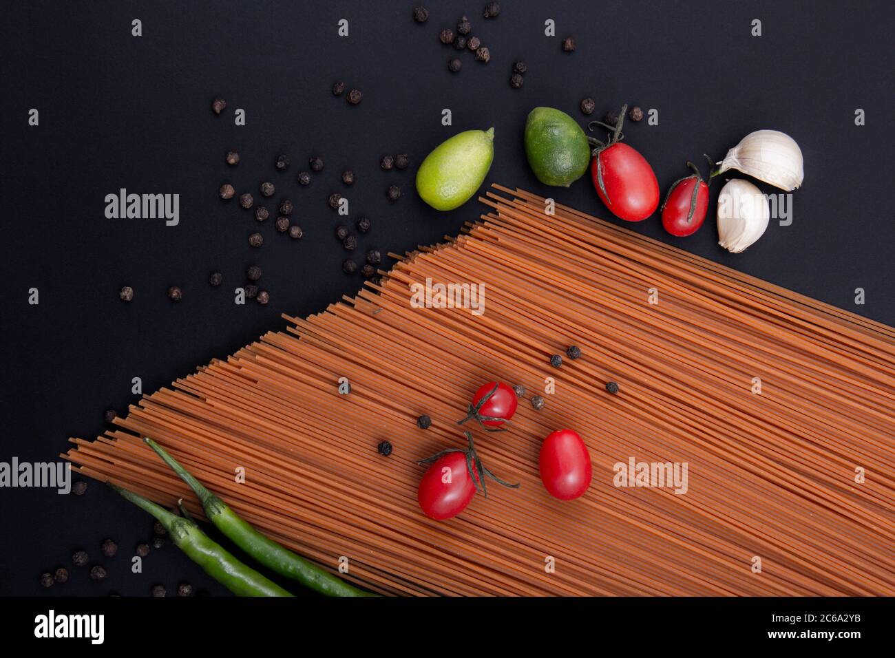 Pasta marrone lunga. Pasta di diverse forme e colori con una varietà di frutta e utensili in legno. Foto Stock