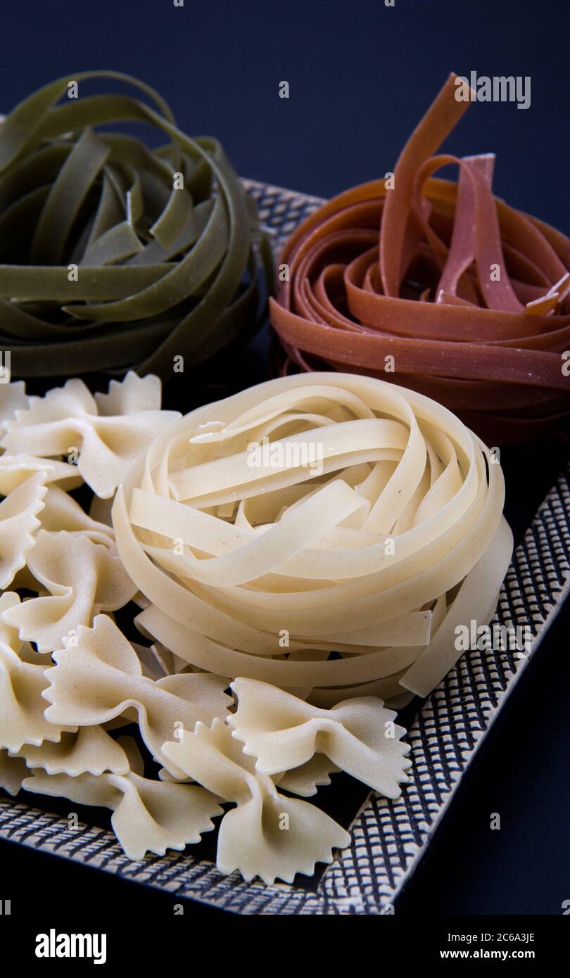 Pasta colorata e sagomata in diverse misure e colori in piccoli piatti insieme a un'ampia gamma. Foto Stock