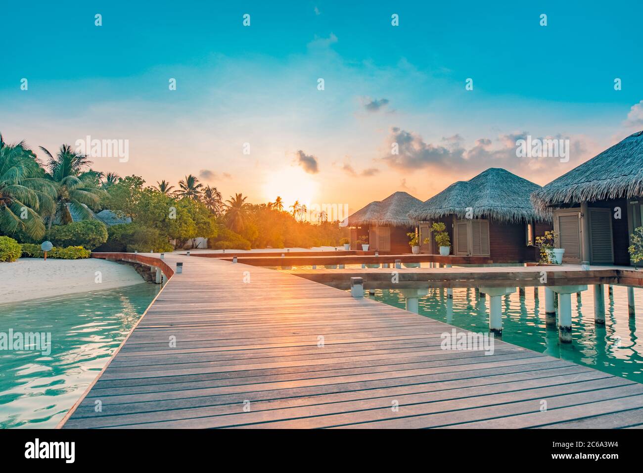 Paesaggio di viaggio incredibile. Tramonto sull'isola delle Maldive, resort di lusso con ville d'acqua e molo in legno. Cielo e nuvole e sfondo della spiaggia Foto Stock