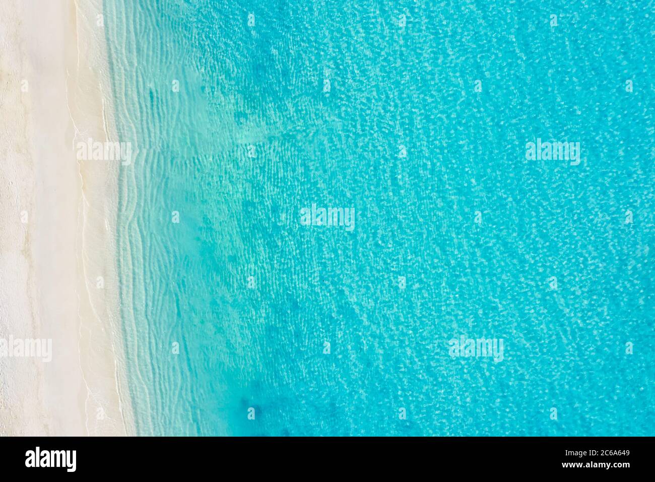 Vista aerea dall'alto di una spiaggia di sabbia bianca sulle rive di un bellissimo mare turchese. Spiaggia di oceano, bellissimo paesaggio, viaggi e vacanze. Foto Stock