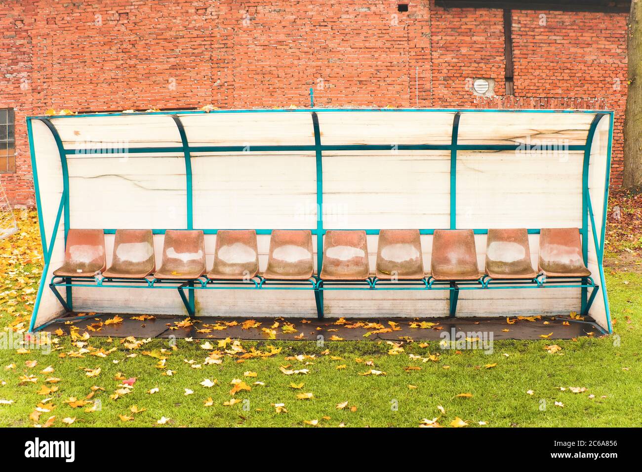 Vecchio banco per giocatori di calcio di riserva, vecchi e rovinati. Mattina d'autunno con foglie caduti Foto Stock