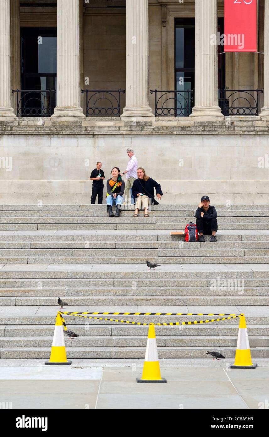 Londra, Inghilterra, Regno Unito. Persone che si siedono sui gradini fino alla Galleria Nazionale in Trafalgar Square durante la pandemia COVID-19, luglio 2020 Foto Stock
