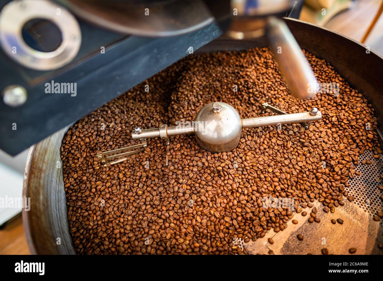 Chicchi di caffè appena tostati da un grande arrosto nel cilindro di raffreddamento. Sfocatura del movimento sui chicchi. Foto Stock