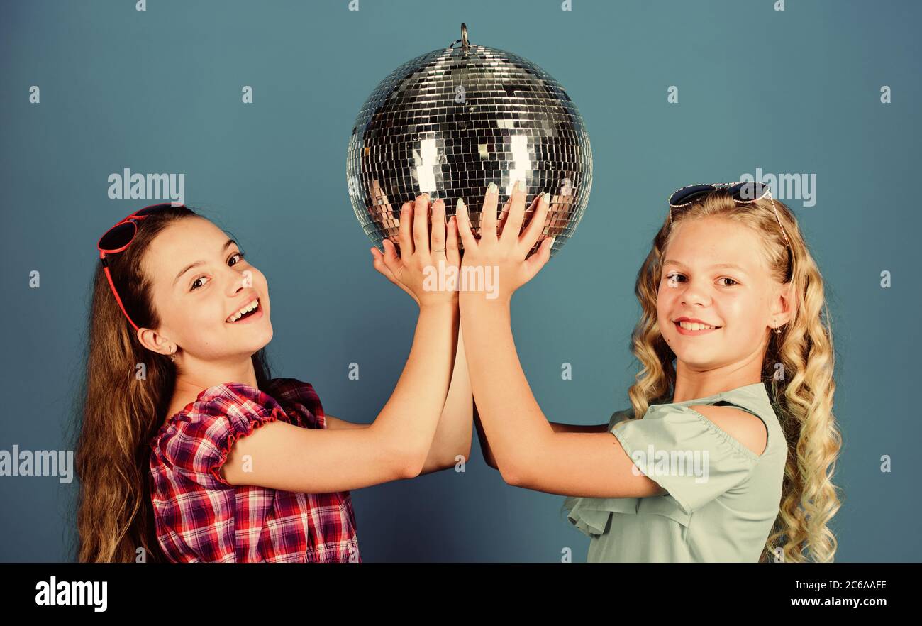 Holiday celebrazione. Concetto di intrattenimento. Sorelle amici con palla da discoteca. Iniziare a parte. Allegro kids tenere palla da discoteca. Discoteca danze. Musica retrò. Gli specchi riflettenti discoteca luci di atmosfera. Foto Stock