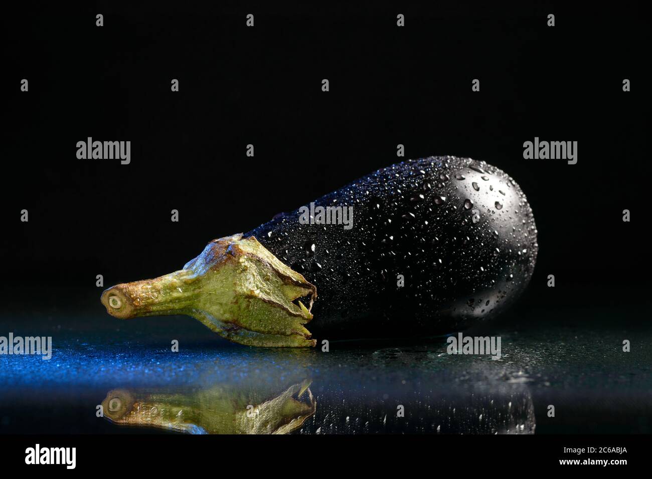 Una melanzana bagnata isolata con un riflesso su sfondo nero Foto Stock