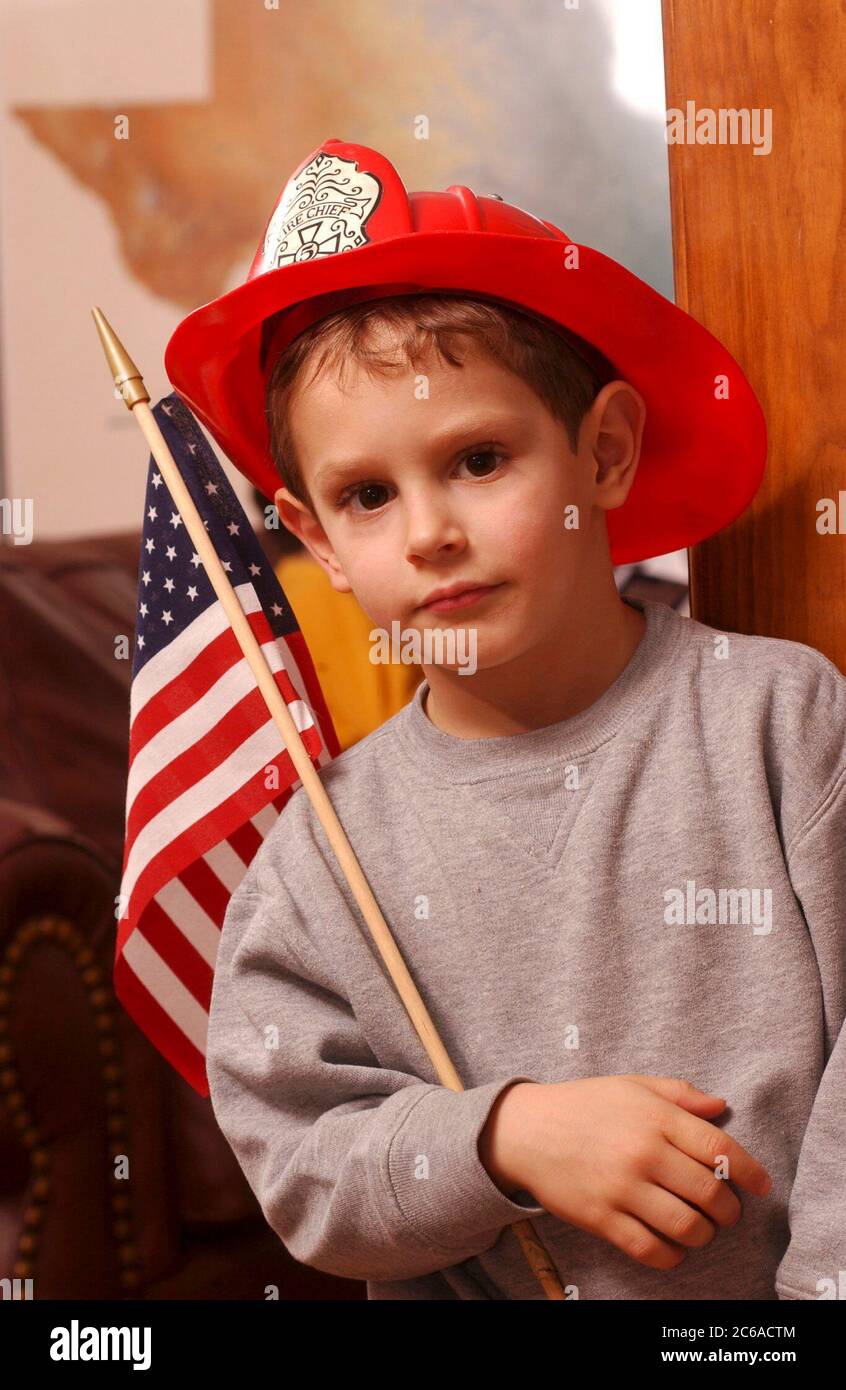 Austin, Texas USA, 31 gennaio 2002: Robin David Daemmrich, 5 anni, posa con un casco da pompiere e una bandiera americana durante il periodo di gioco. Dice che vuole essere un coraggioso pompiere quando cresce. ©Bob Daemmrich Foto Stock