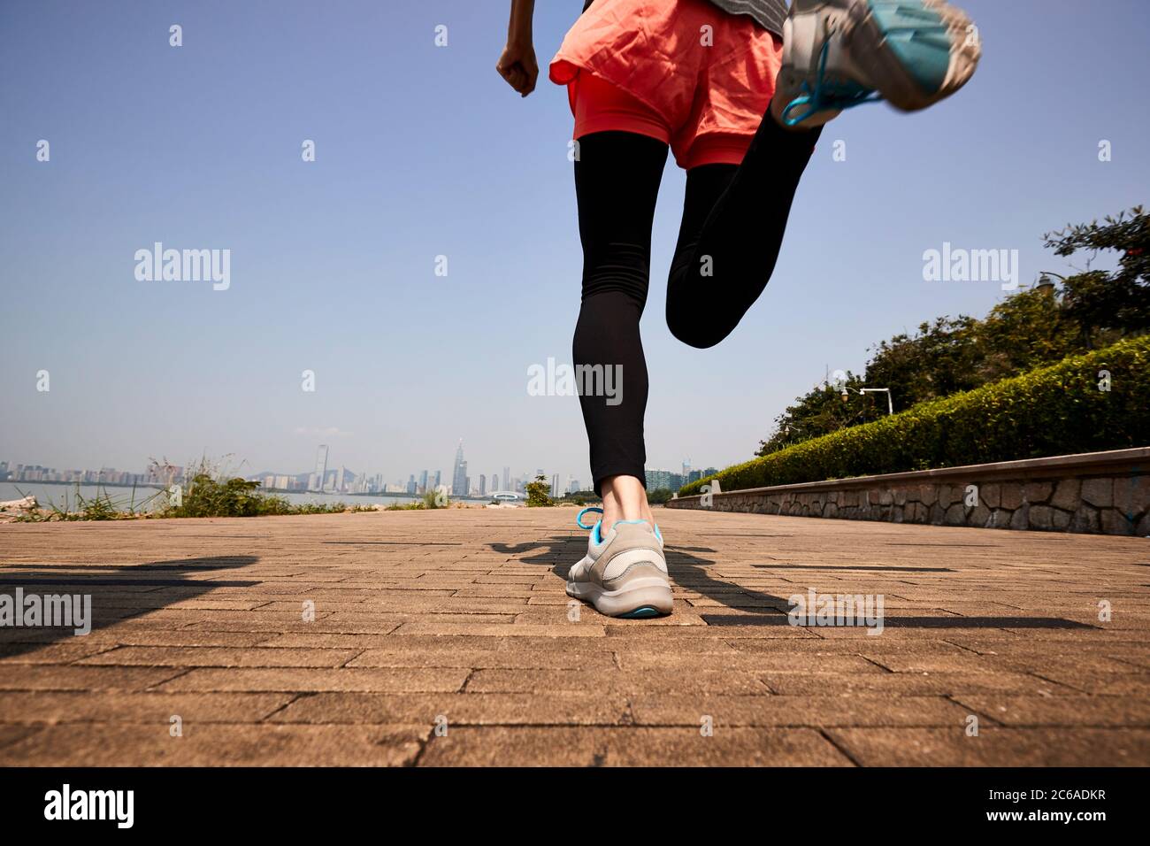 giovane donna asiatica adulta che corre jogging all'aperto, vista posteriore e angolo basso Foto Stock