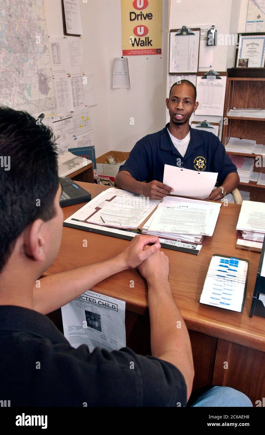 Austin Texas USA, 2003: Un ufficiale afro-americano di libertà vigilata incontra nel suo ufficio con un parolee ispanico per discutere di stare fuori dai guai mentre è in libertà vigilata. Modelli rilasciati ©Bob Daemmrich Foto Stock