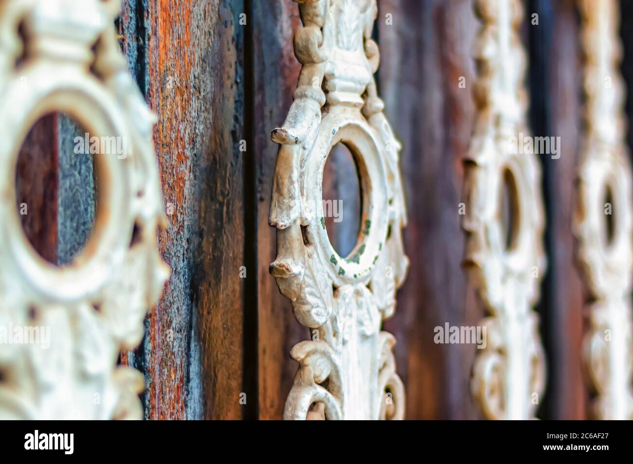 Un primo piano di ringhiere decorative contro le tavole di legno intemperie al Palazzo di Chowmahalla, Hyderabad, Telangana, India. Foto Stock