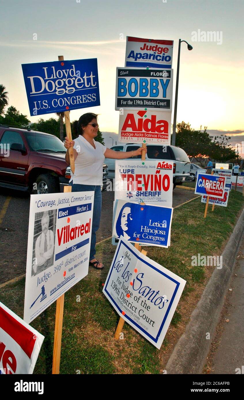 Edinburg, Texas USA, 9 marzo 2004: Operaio elettorale circondato da cartelli fuori dalla città del Texas meridionale di Edimburgo durante le elezioni primarie della primavera 2004. ©Bob Daemmrich Foto Stock