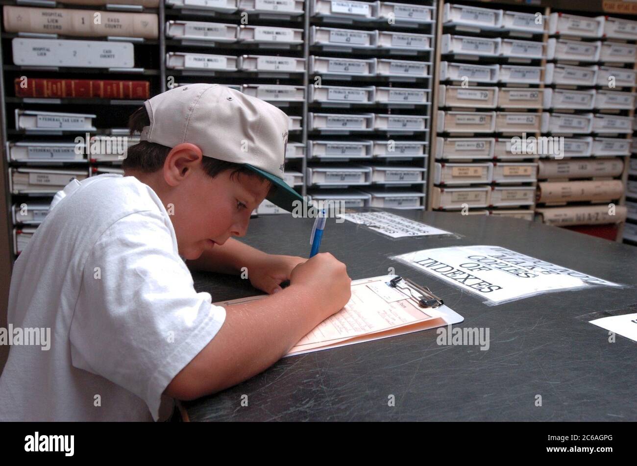 Cass County, Linden, Texas USA, luglio, 2004 un ragazzo di dieci anni scrive mentre si trova nella contea un archivio di documenti pubblici presso il tribunale della contea di Cass, il più antico tribunale occupato del Texas. ©Bob Daemmrich Foto Stock