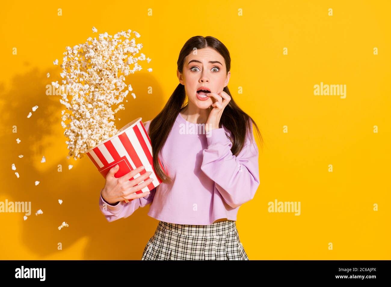 Ritratto di ragazza ansiosa guardare film horror sentire paura tocco i  denti trattengono la grande scatola pop corn volanti che cade usura  ponticello a cavallotto isolato su luminoso Foto stock - Alamy