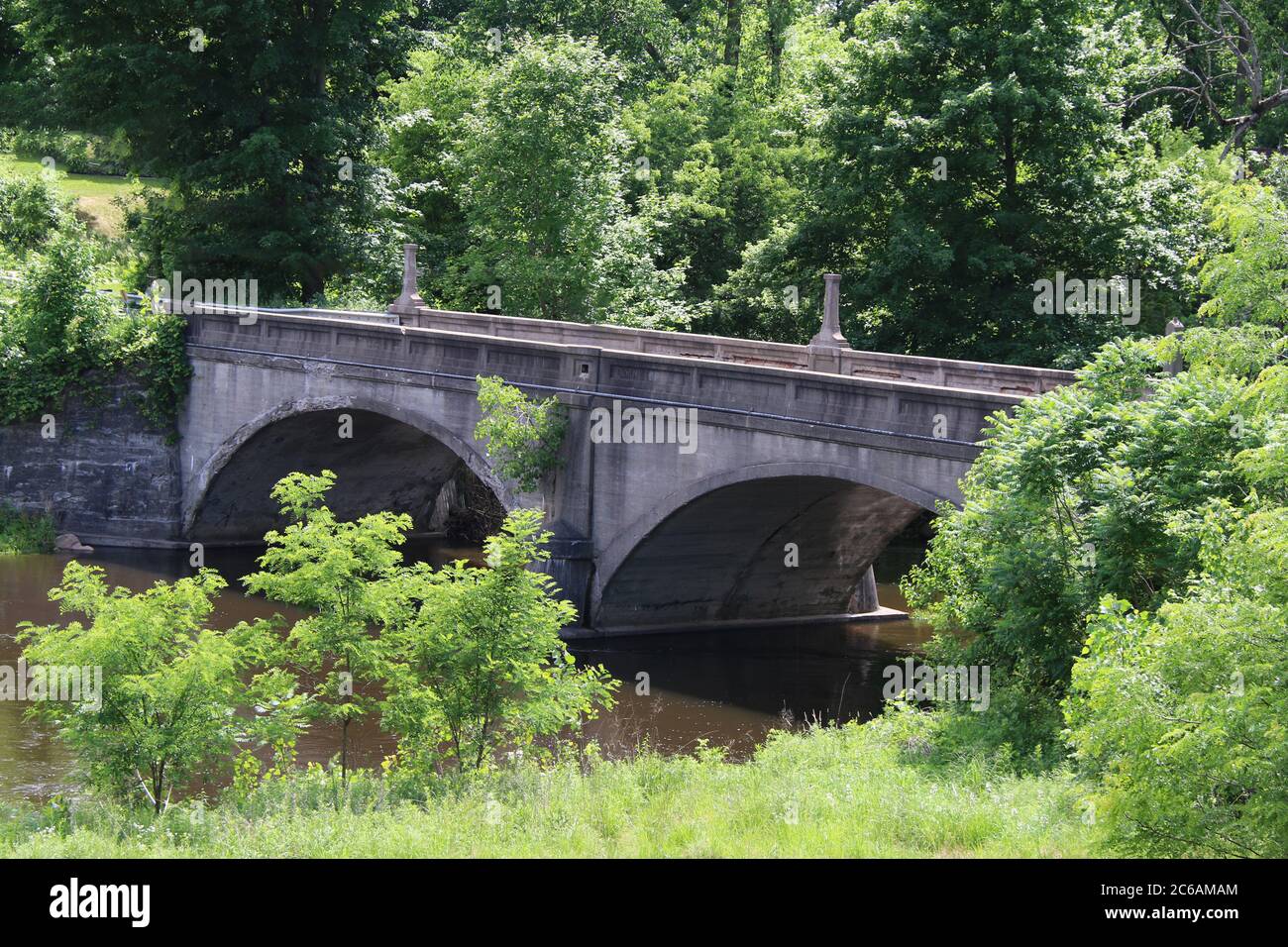 un vecchio ponte ad arco su un fiume di campagna Foto Stock