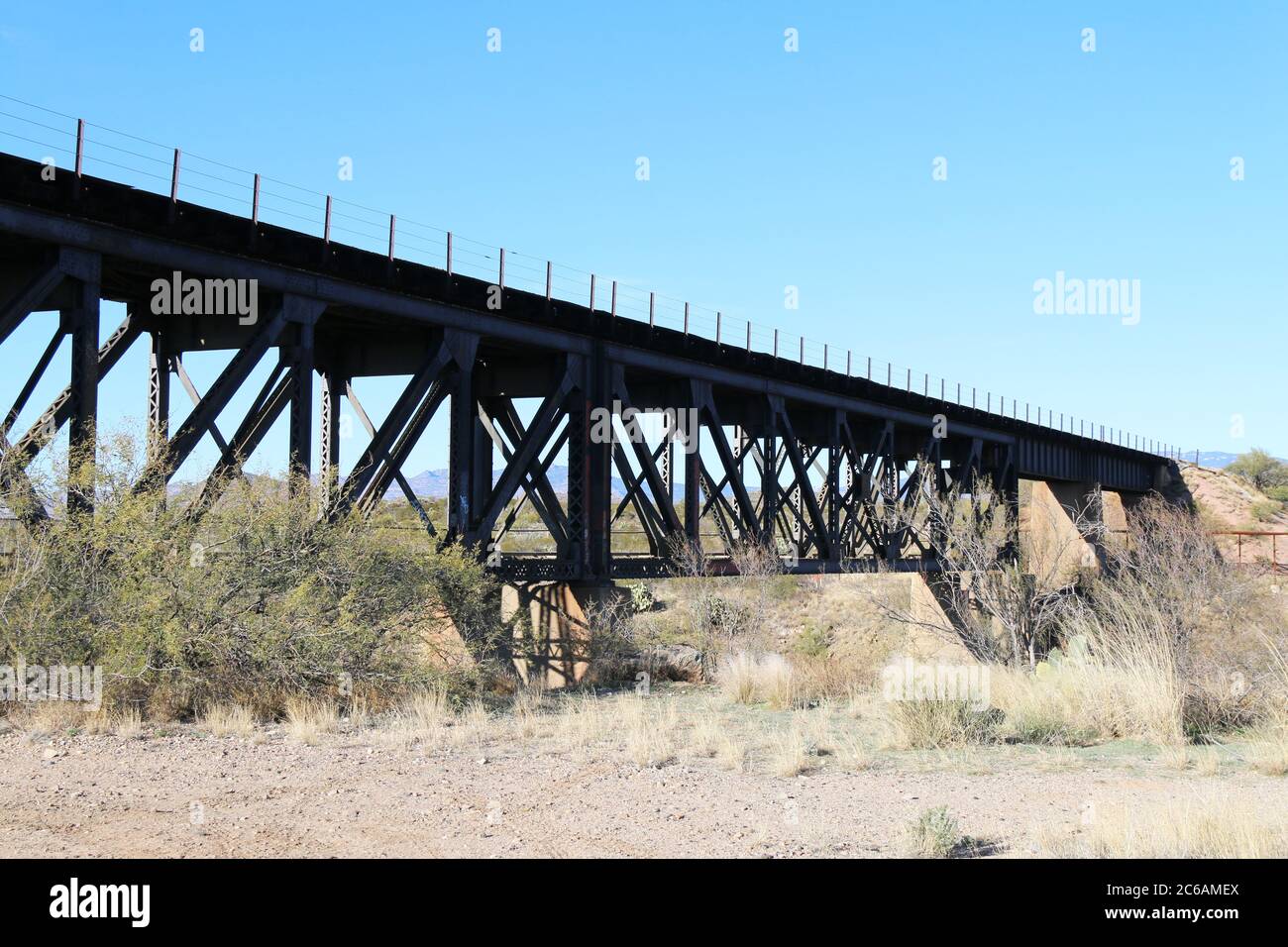 un ponte ferroviario alto su una gola del deserto con cielo blu Foto Stock