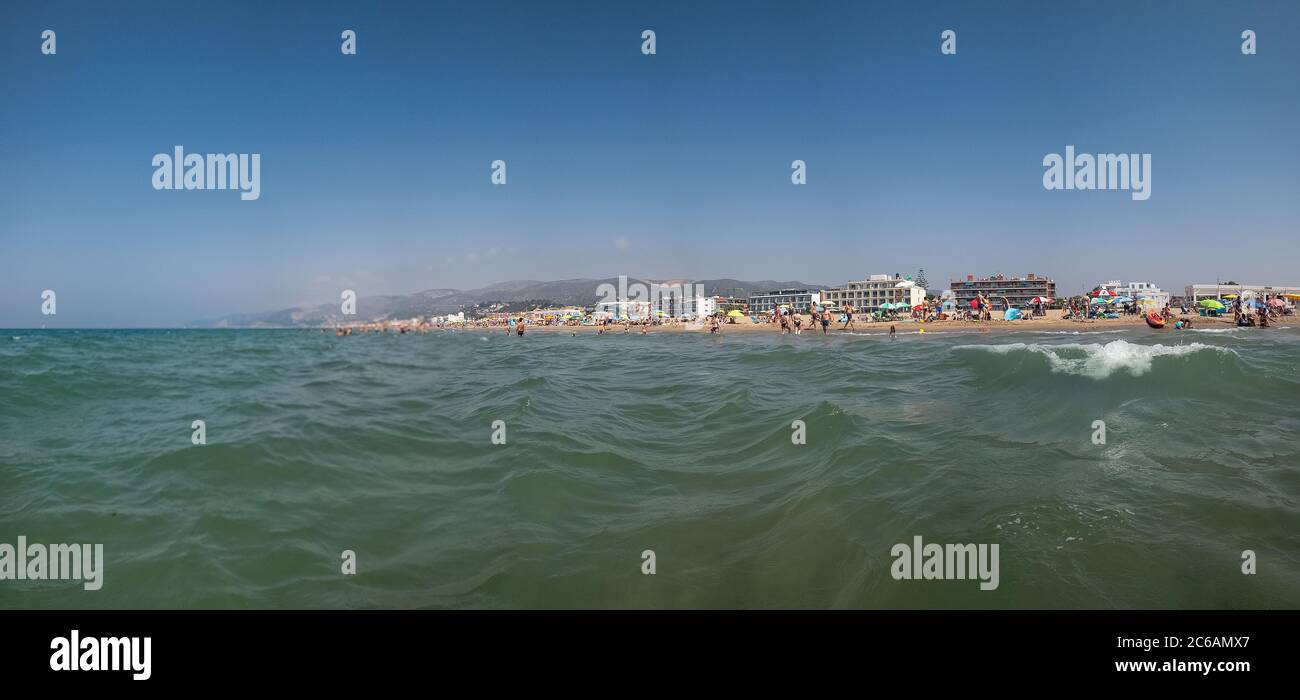 Scena di vacanza. Vista dall'acqua di mare e un'onda in una destinazione di viaggio con una spiaggia all'orizzonte. Foto Stock