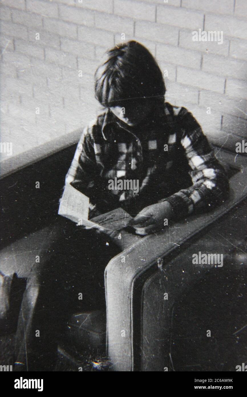 Fine anni 70 vintage nero e bianco stile di vita fotografia di una ragazza boyish che legge un pamphlet. Foto Stock
