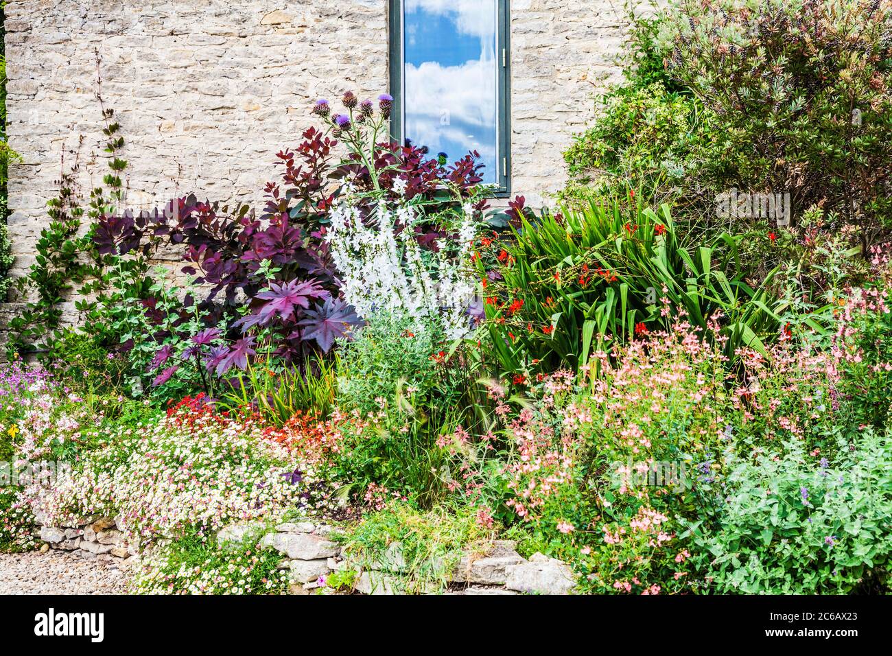 Un confine erbaceo sotto la finestra di un moderno cottage in pietra. Foto Stock