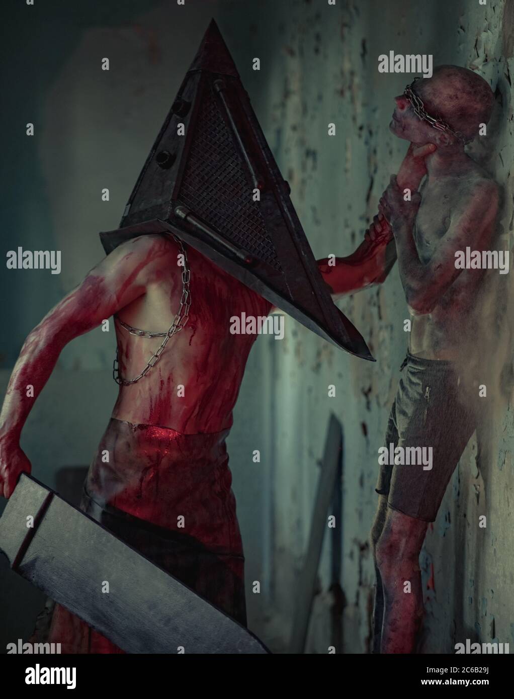 I cosplayer sono in immagine di mostro con gli occhi legati con catene e carnefice in camera oscura. Foto Stock