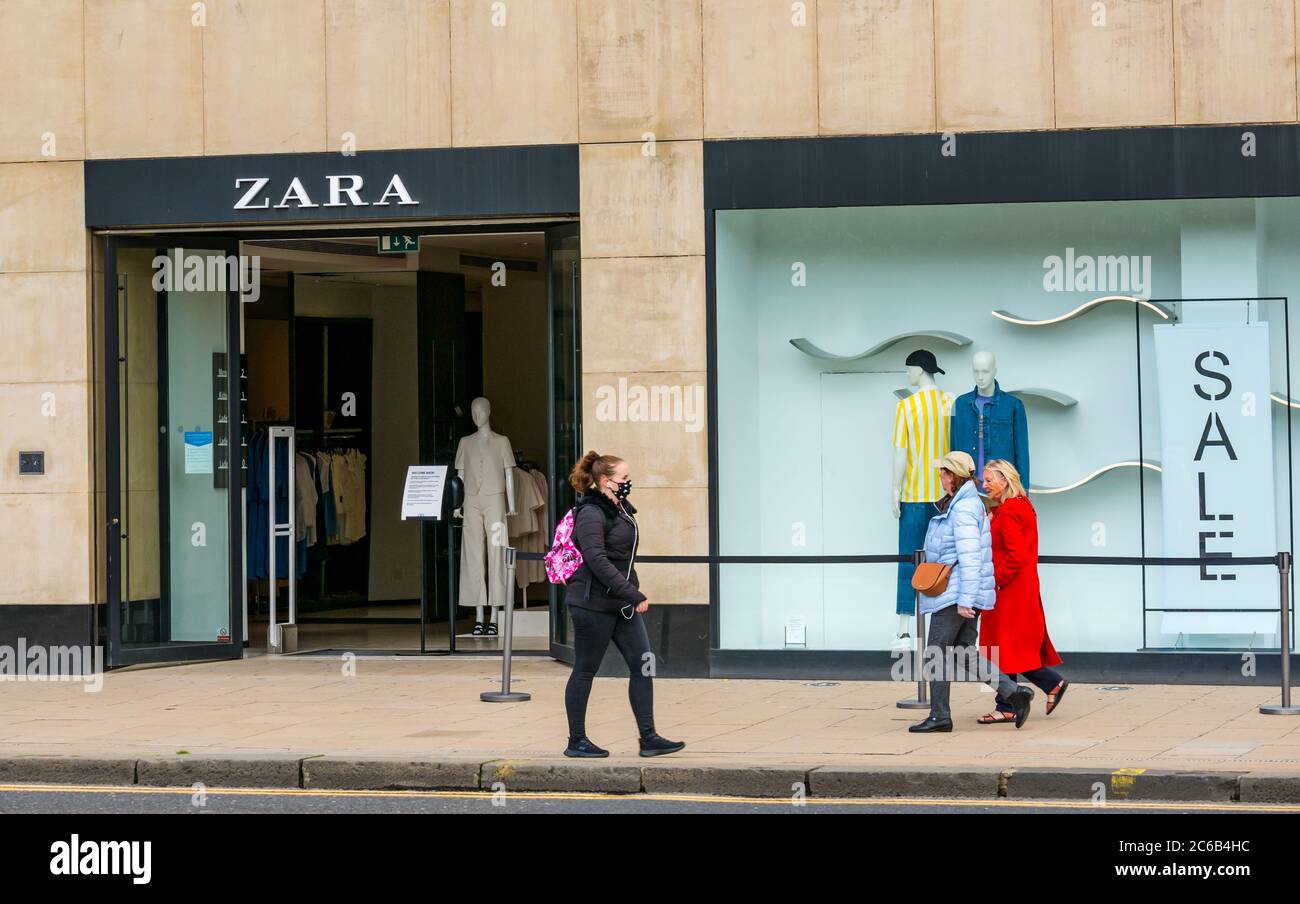 Gli acquirenti passano accanto al negozio di abbigliamento Zara; una donna che indossa una maschera durante la pandemia, Princes Street, Edimburgo, Scozia, Regno Unito Foto Stock