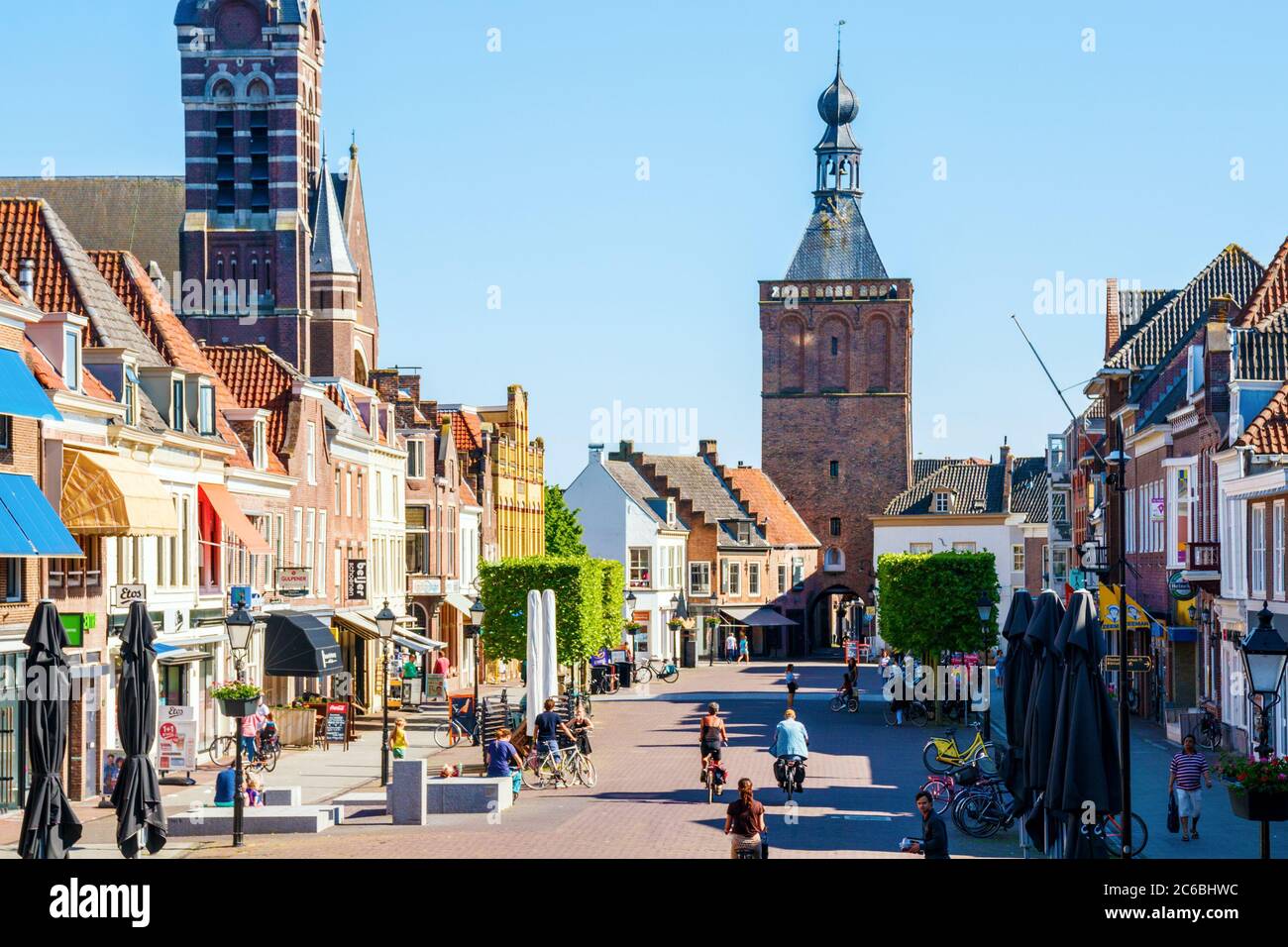 Culemborg. Vista sulla Piazza del mercato con negozi, vecchie case e il medievale Binnenpoort (porta della città) in un pomeriggio di sole. Paesi Bassi. Foto Stock
