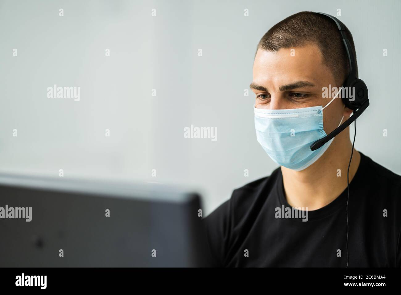 Operatore telefonico di Call Center in ufficio con maschera facciale Foto Stock