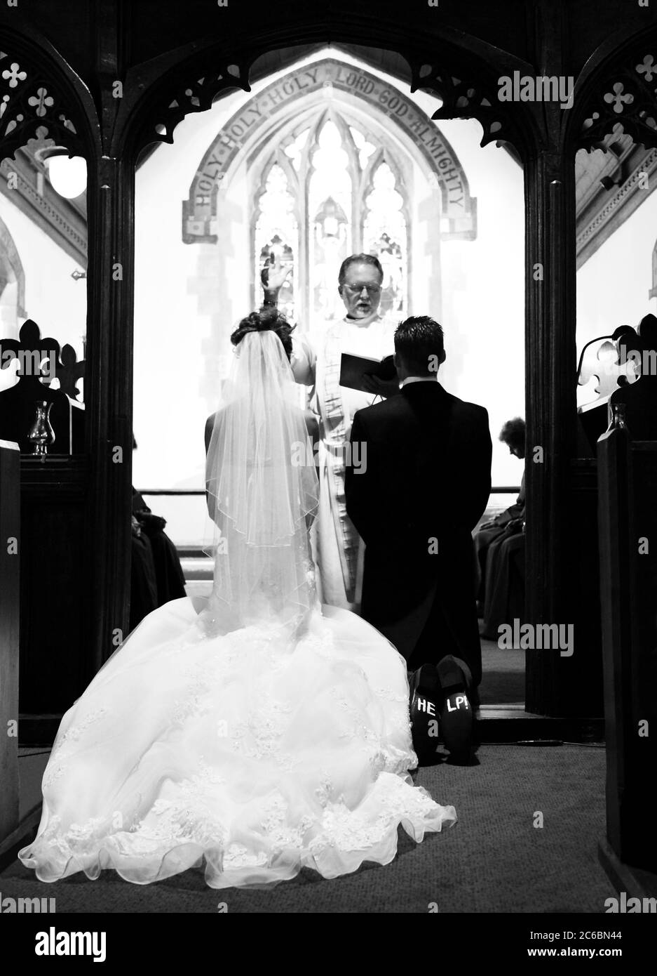 Aiuto' scritto sulle suole delle scarpe di uno sposo, visibile mentre sposa  e sposo si inginocchiano per la benedizione in una chiesa di nozze Foto  stock - Alamy