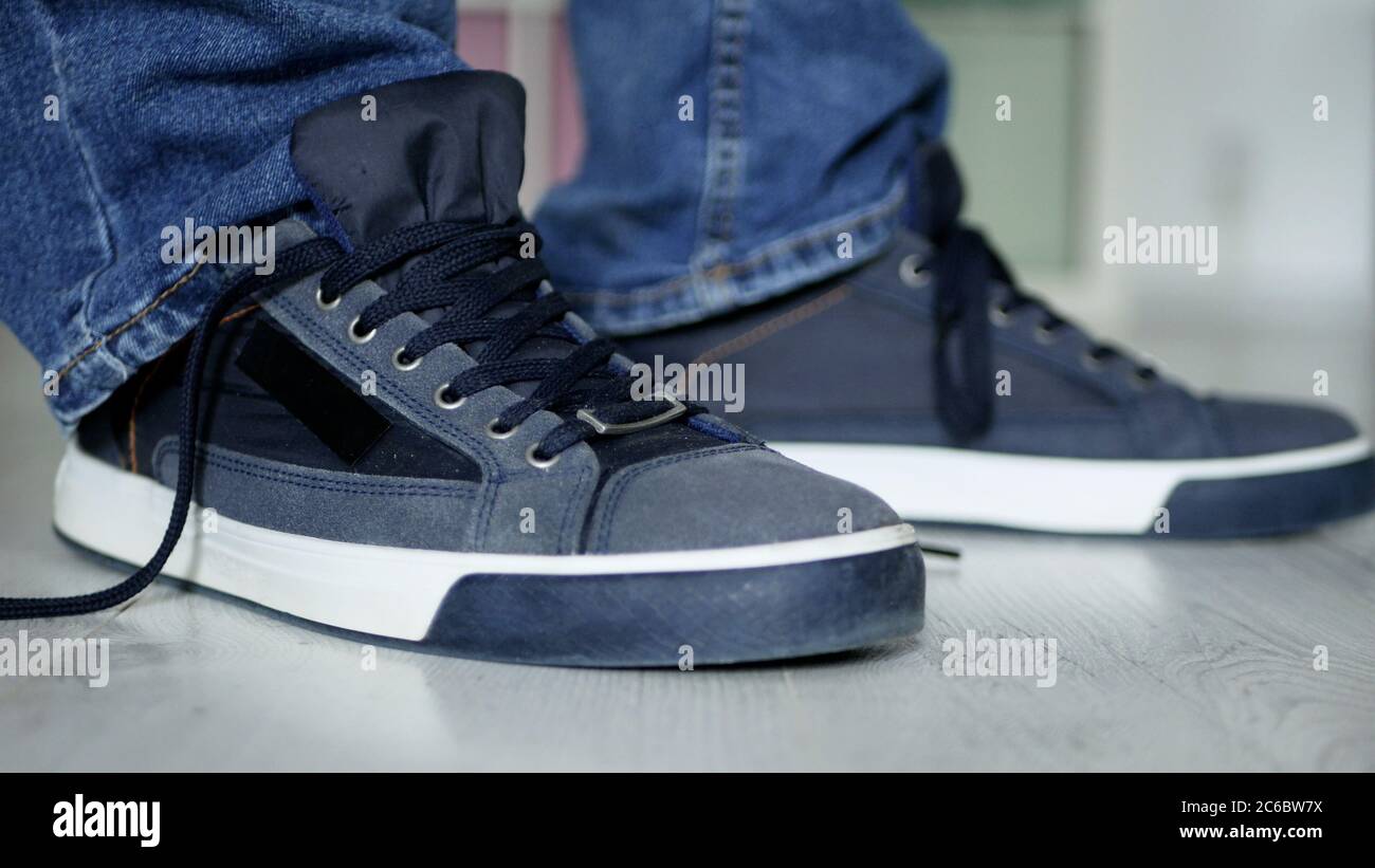 Uomo che si prepara per una passeggiata con Laces Unlegato sulle sue scarpe sportive Foto Stock