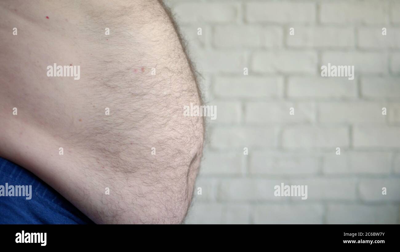 Uomo obese che mostra il suo venticcio grasso, una persona affamata che misura il suo grasso ventoso, problemi di salute di un vecchio uomo con obesità Foto Stock