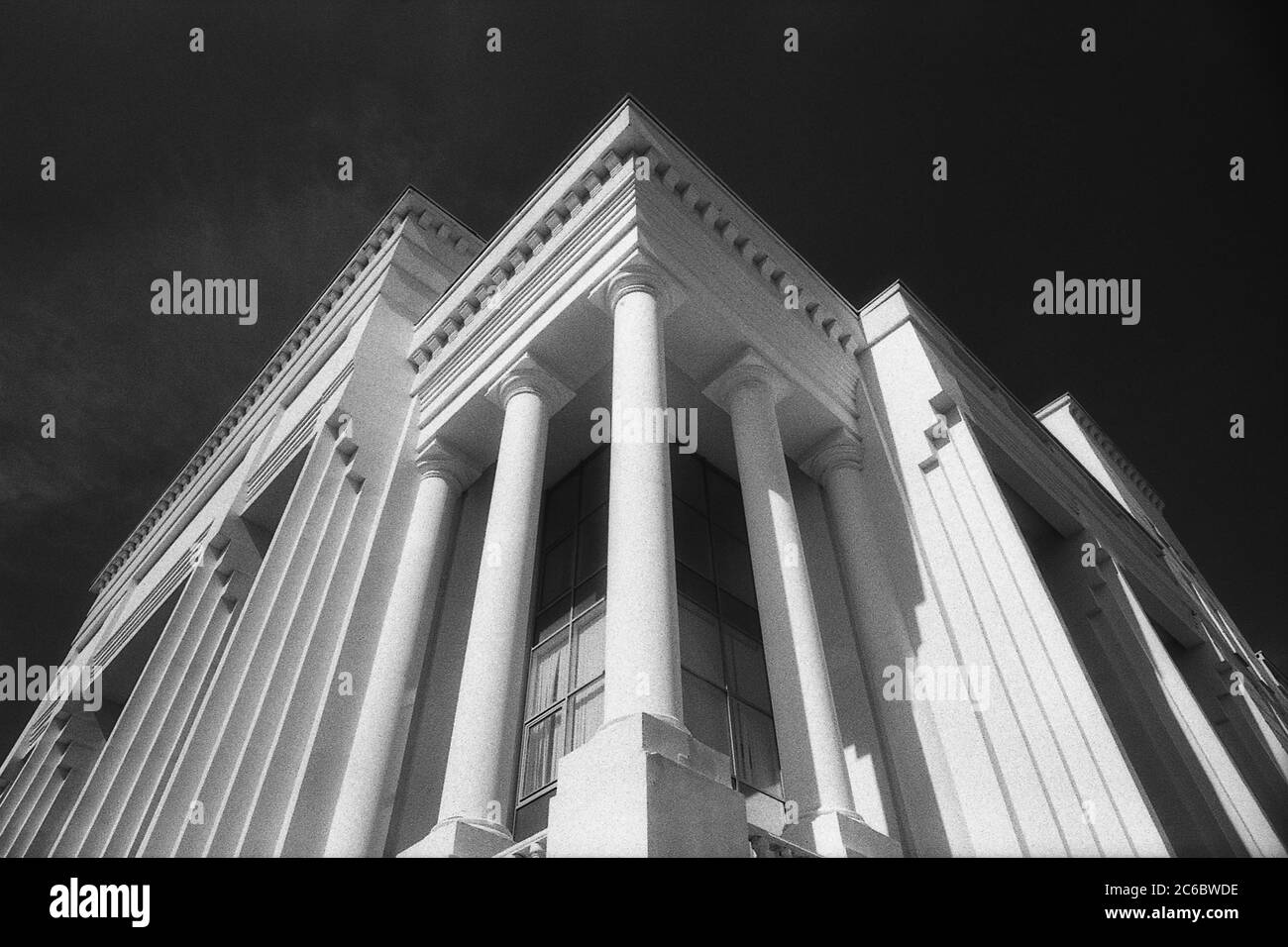 Architettura moderna. Immagine granulosa in bianco e nero di un imponente edificio con colonne contro lo spazio di copia del cielo nero Foto Stock