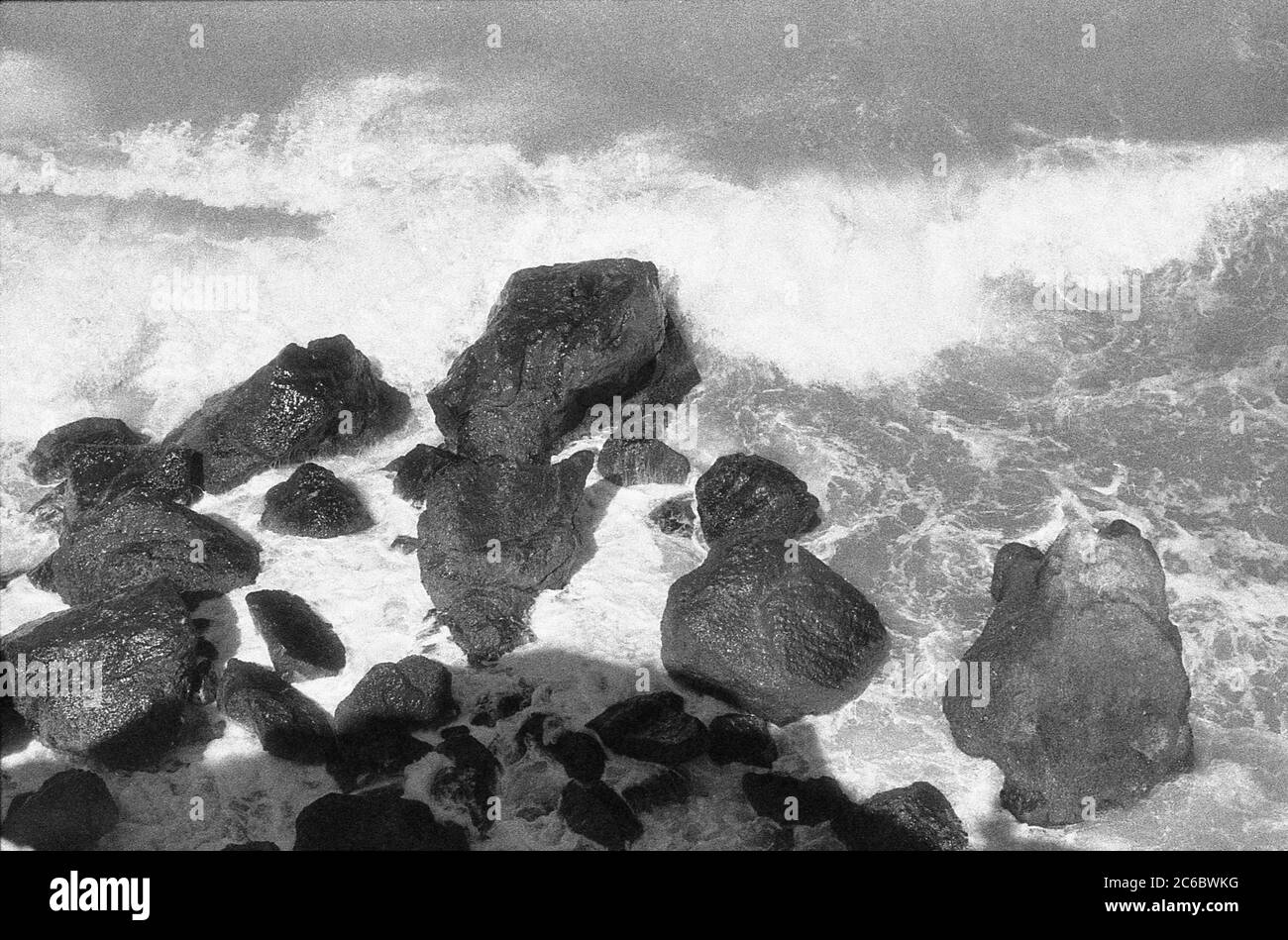 Concetto di immagine sgranata vintage in bianco e nero. Rocce vuote in onde di mare schiumose orizzontali Foto Stock