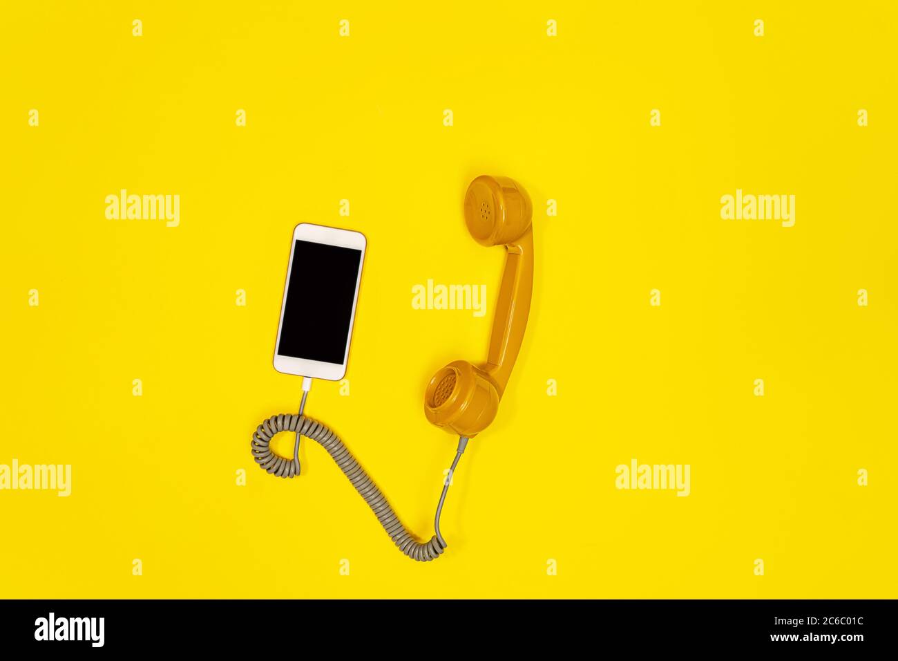 Telefono cellulare e telefono vecchio stile su sfondo giallo. Moderno stile retrò. Nuova vecchia tecnologia. Foto Stock