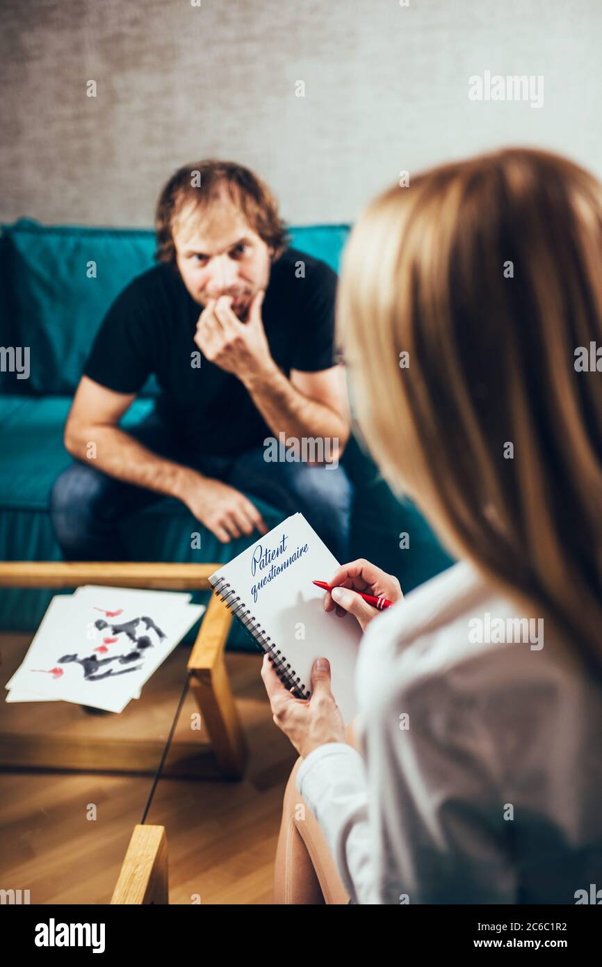 Una psicologa donna alla consultazione redige un questionario per un paziente di un uomo - assistenza psicologica professionale - crisi di mezza età Foto Stock