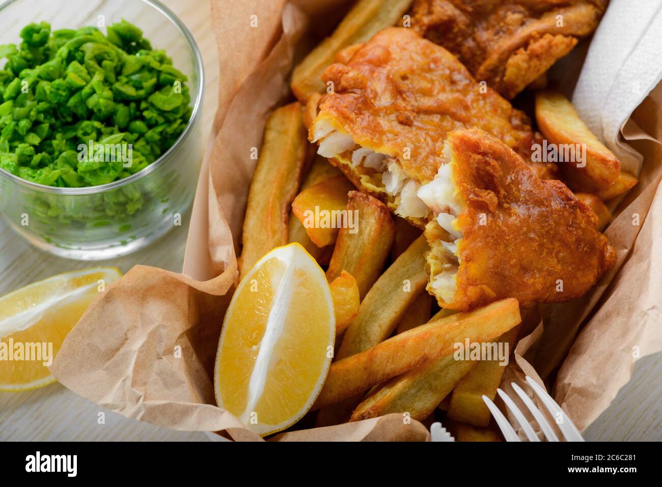 Pesce e patatine fatte in casa con limone e piselli verdi Foto Stock