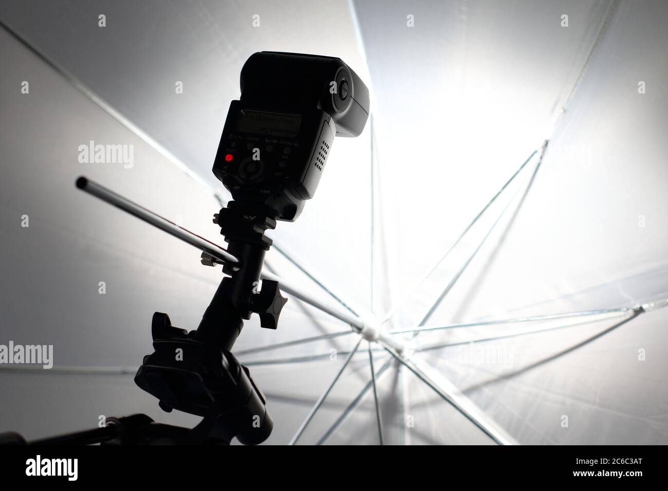 Il flash della fotocamera lampeggia in un ombrello bianco nello studio fotografico. Foto Stock