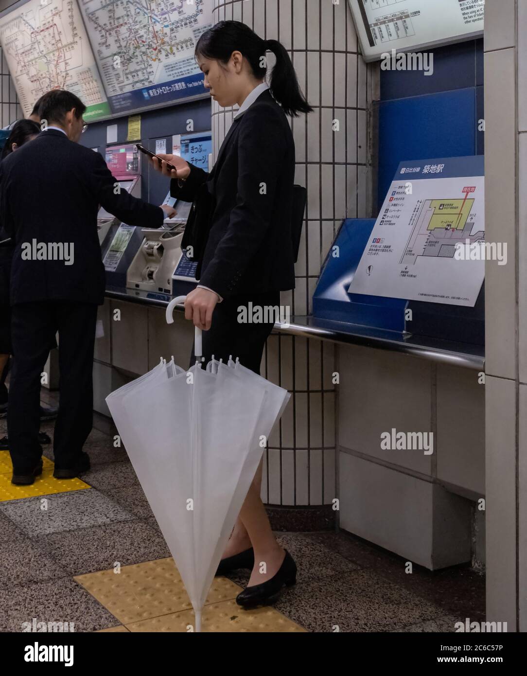 Lavoratore femminile in ufficio con un costume da lavoro con smartphone in una stazione della metropolitana di Tokyo, Tokyo, Giappone Foto Stock