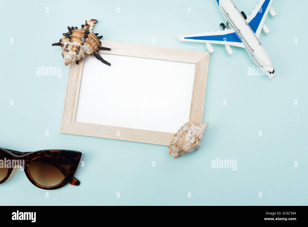 Concetto di viaggio mock up con cornice, decorazione di aeroplano e  occhiali da sole e conchiglie su sfondo blu. Disposizione piatta con spazio  per la copia Foto stock - Alamy