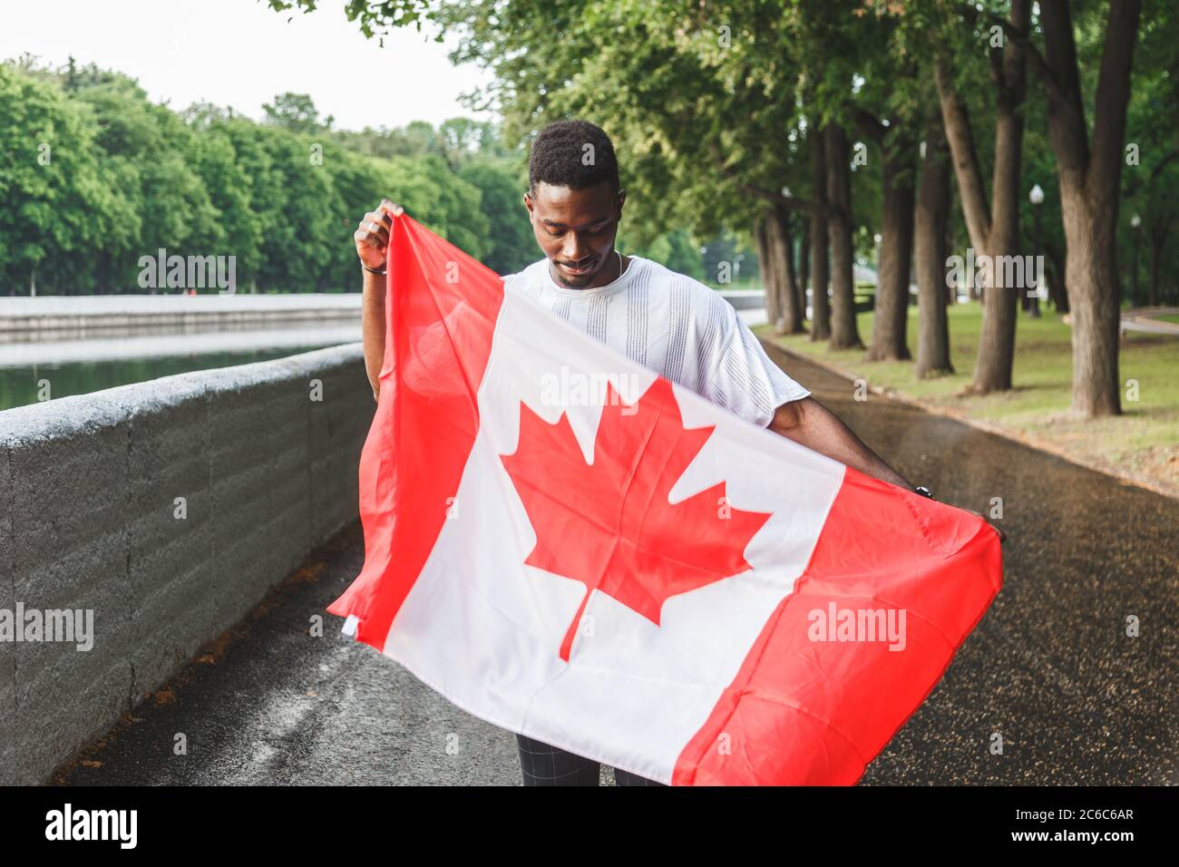 Bell'uomo afro-americano con bandiera canadese, in piedi all'aperto. Foto Stock