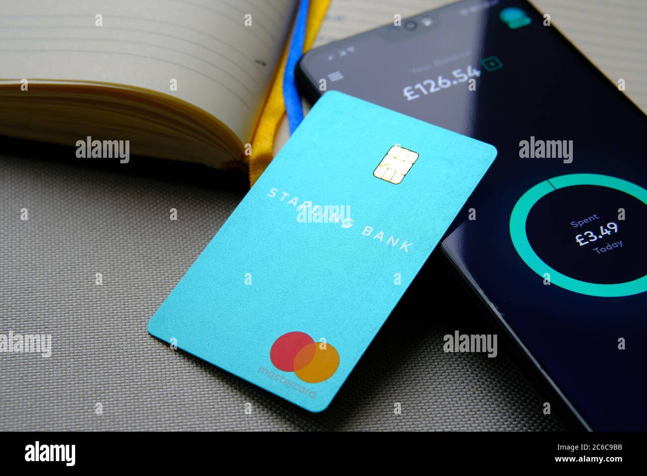 Stone / UK - 8 luglio 2020: La carta Starling Bank è posizionata sulla parte superiore dello smartphone con l'app Starling che mostra il saldo sullo schermo. Foto Stock