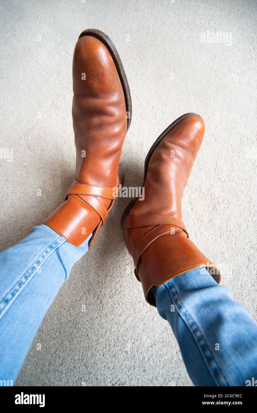 Stivali marroni con fibbia indossata su jeans blu. Uno stile simile a chelsea o stivali da cowboy. Moda, stile, trendy, vintage. Foto Stock